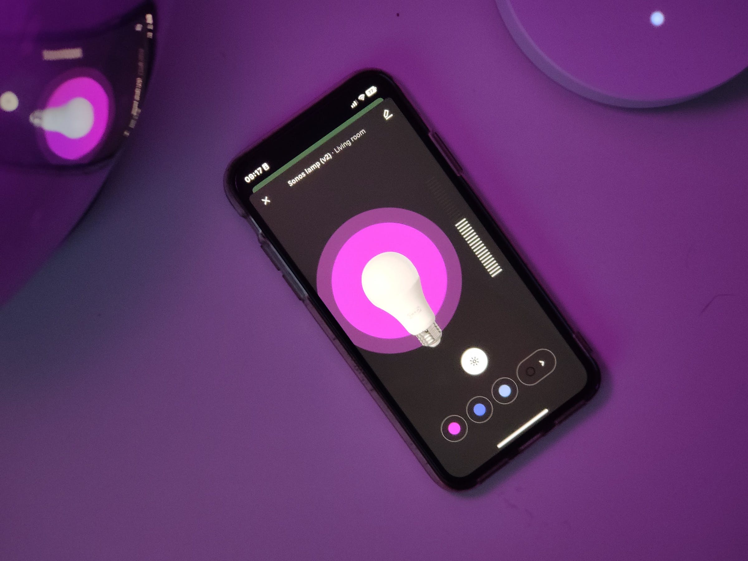 Un iPhone exécutant la nouvelle application Home est montré en train de régler une lumière sur la couleur rose alors que le téléphone est inondé de lumière rose.